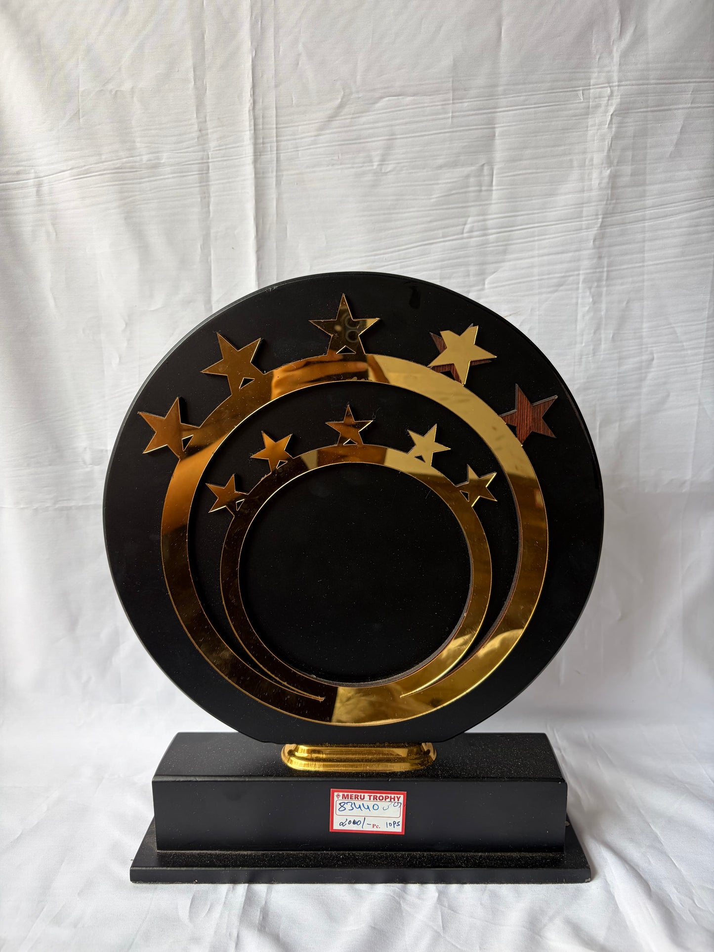 Elegant 83440 decorative plaques with gold star accents and concentric rings on a black circular stand for awards.