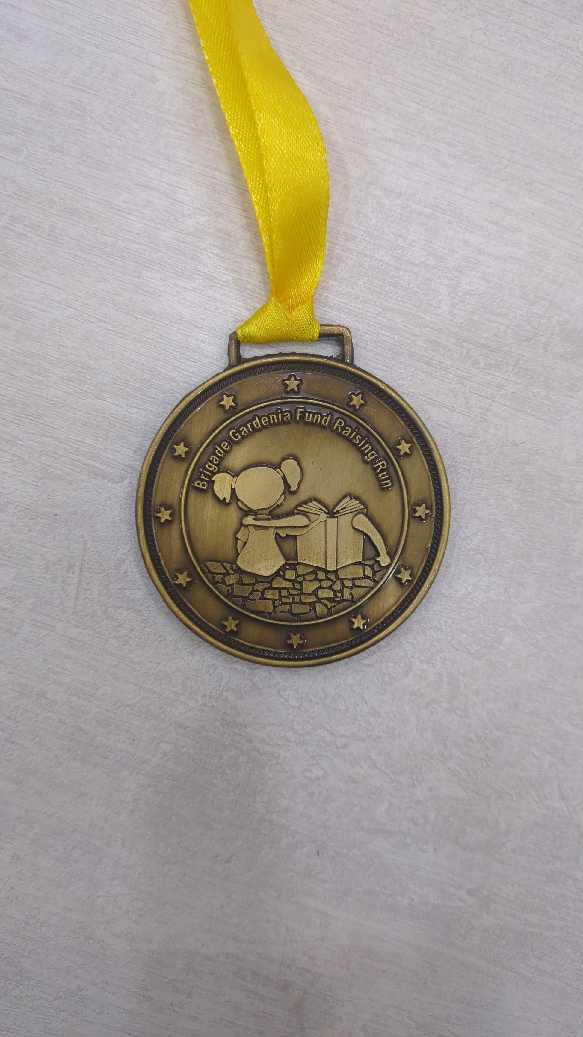 Bronze custom medal featuring a girl reading; perfect for academic awards and student recognition.